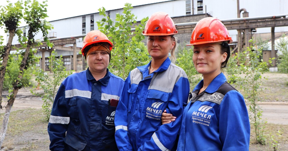 Рабочие на заводе в строительных касках.