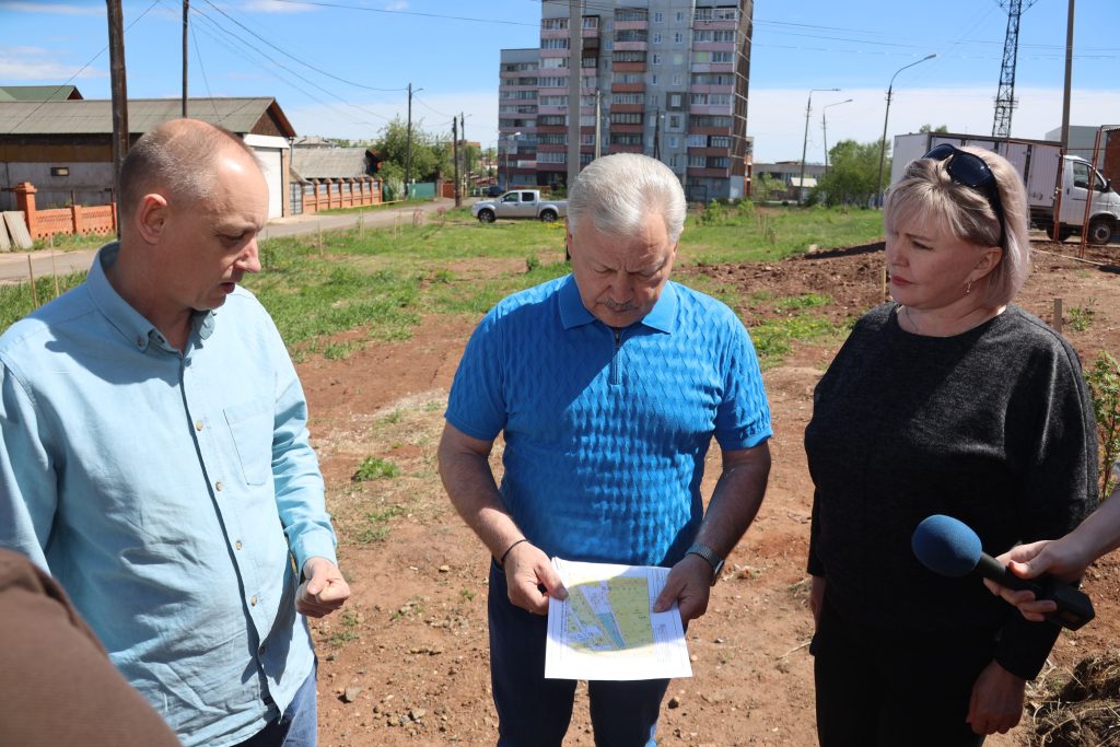 Люди обсуждают план строительства на свежем воздухе.