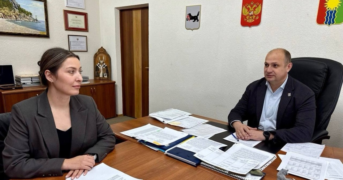 Собрание в офисе, двое сотрудников обсуждают документы.