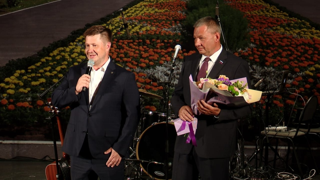 Два мужчины на сцене с микрофоном и цветами