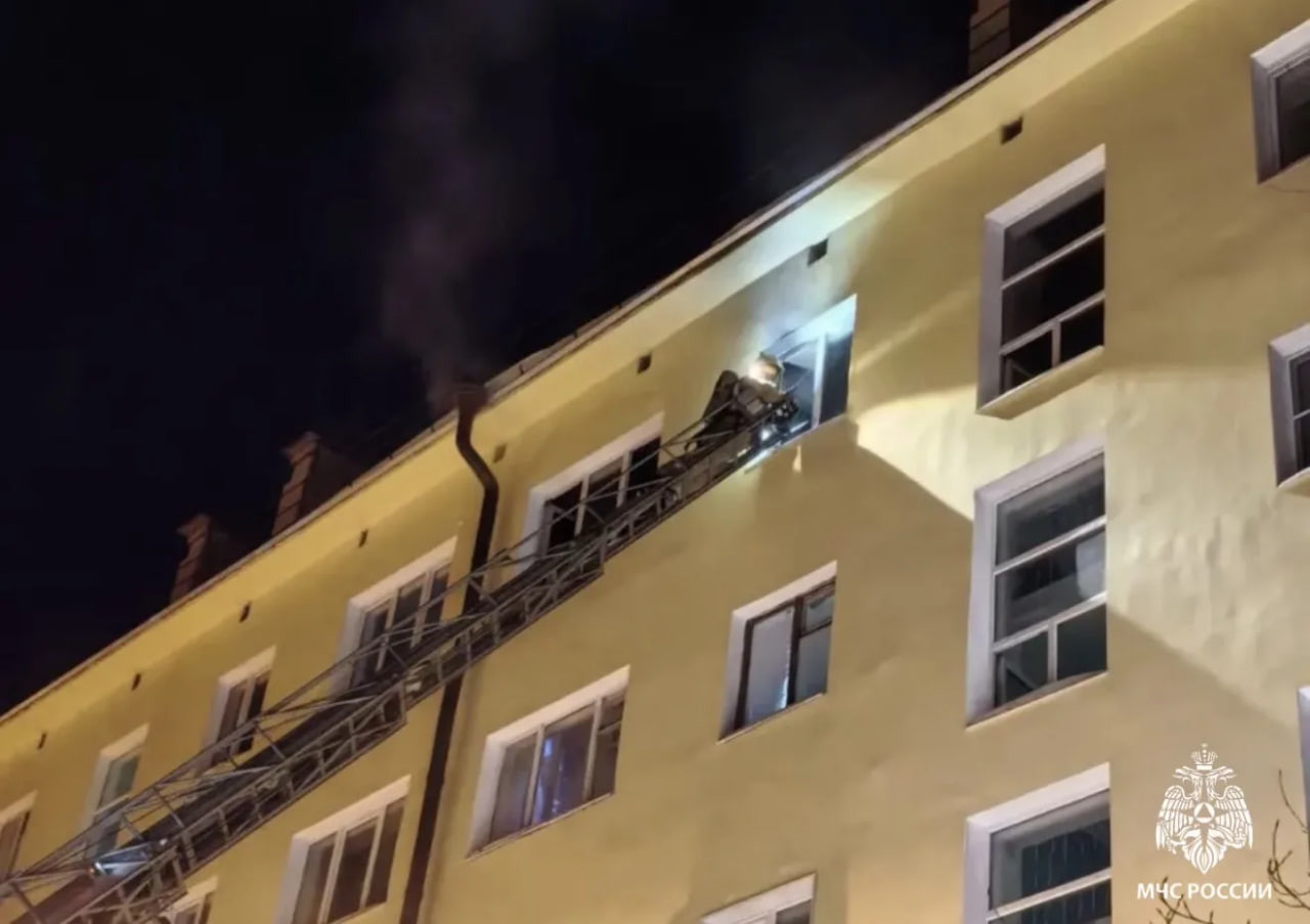 Пожарные спасают людей из горящего дома ночью.