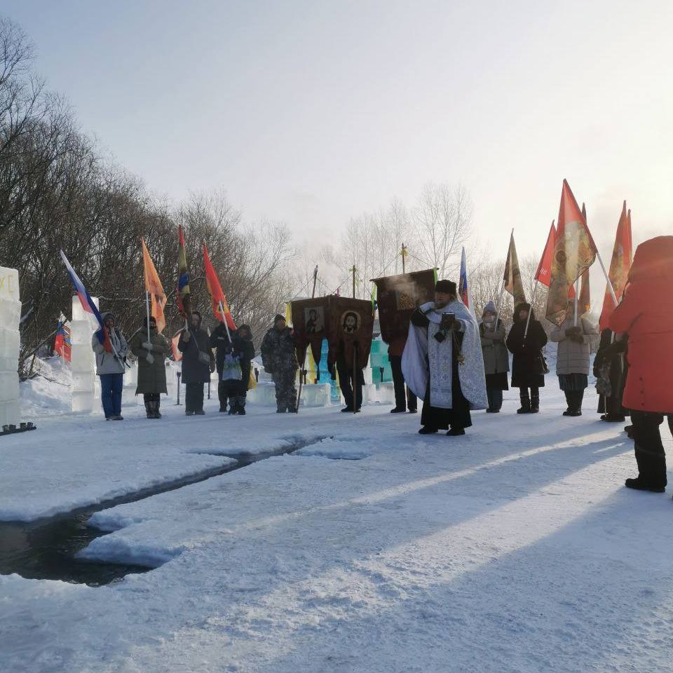 Церковная процессия зимой с флагами на снегу.