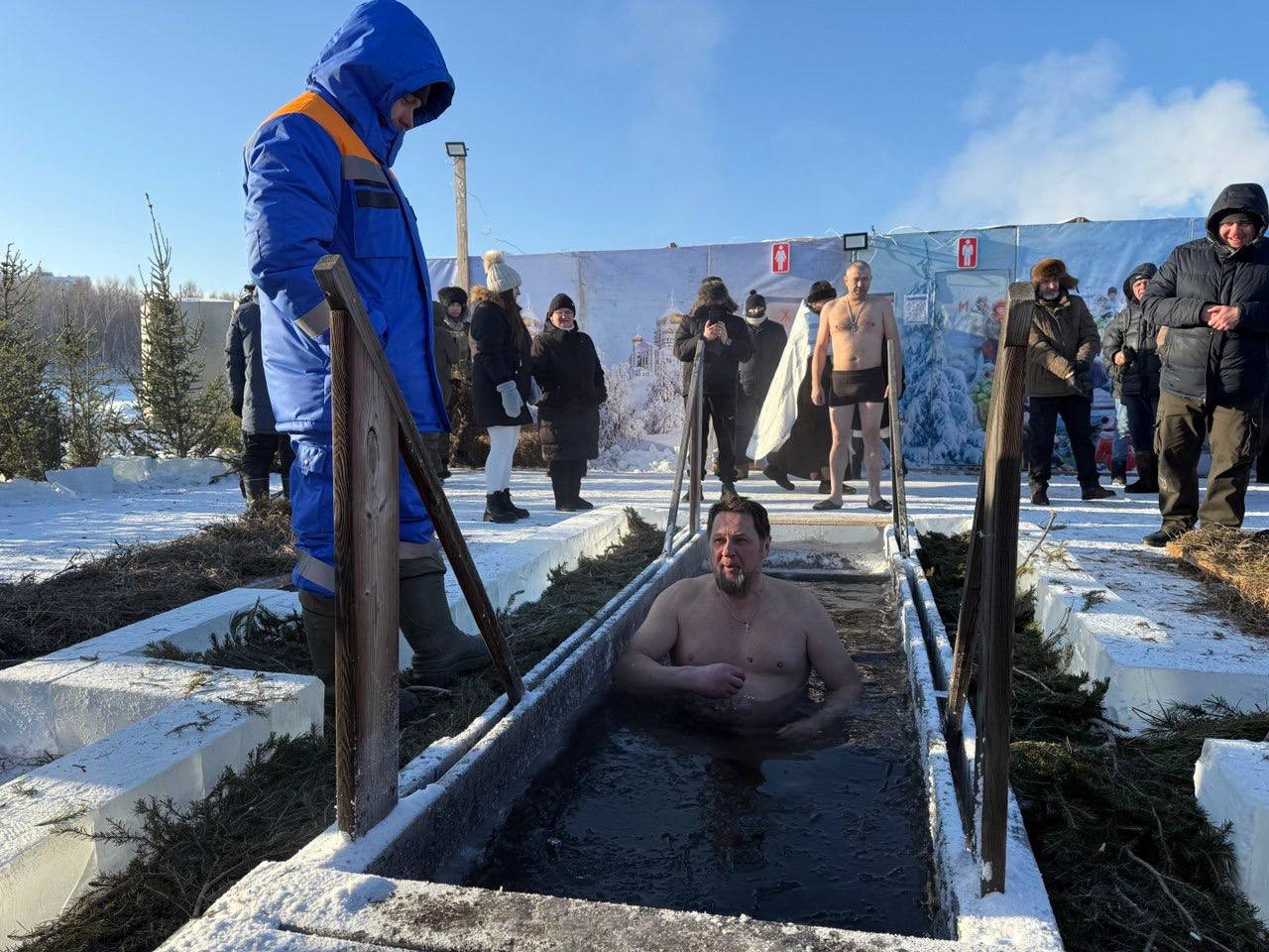Человек купается в проруби на зимнем празднике.