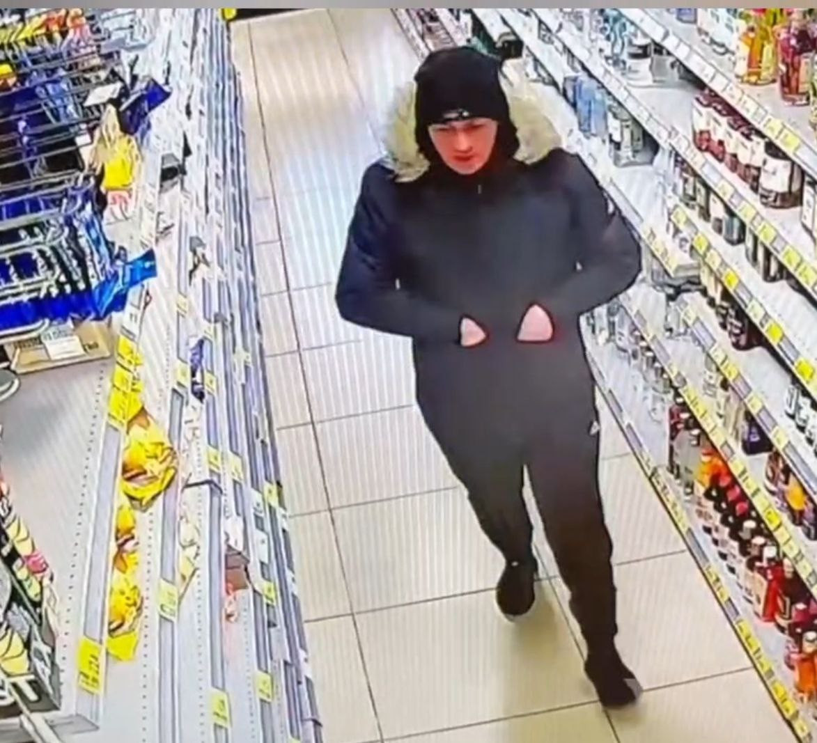 Мужчина в магазине, между полками с товарами.