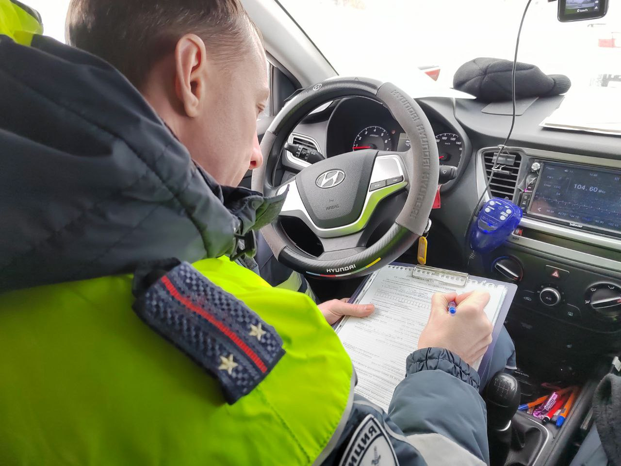 Полицейский заполняет документы в патрульной машине.