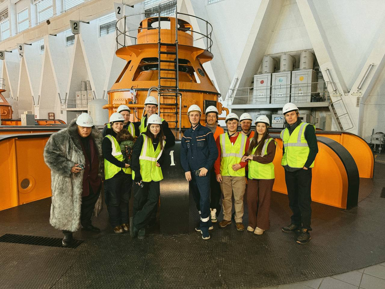 Группа людей в касках на заводском фоне