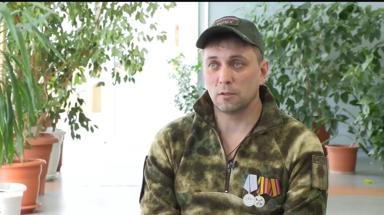 Мужчина в камуфляже с медалями в помещении