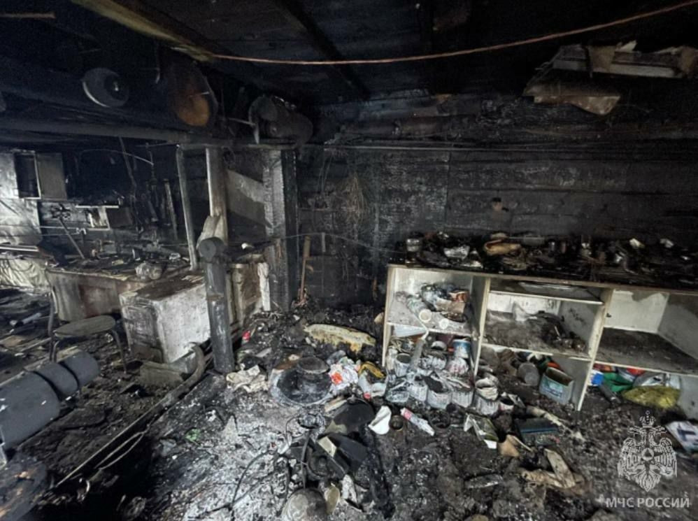 Послепожарные повреждения в комнате, обгоревшая мебель.