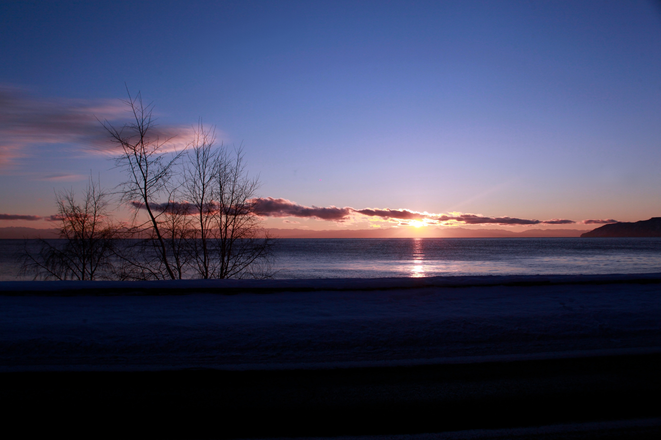 Закат над зимним озером с деревьями